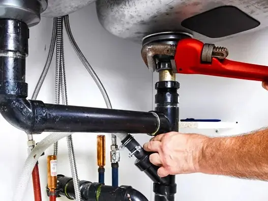 Plumber connecting sink supply lines and drain under a vanity