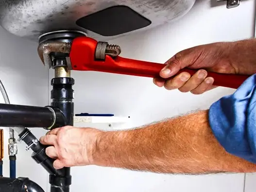 Plumber using a pipe wrench on a residential plumbing repair